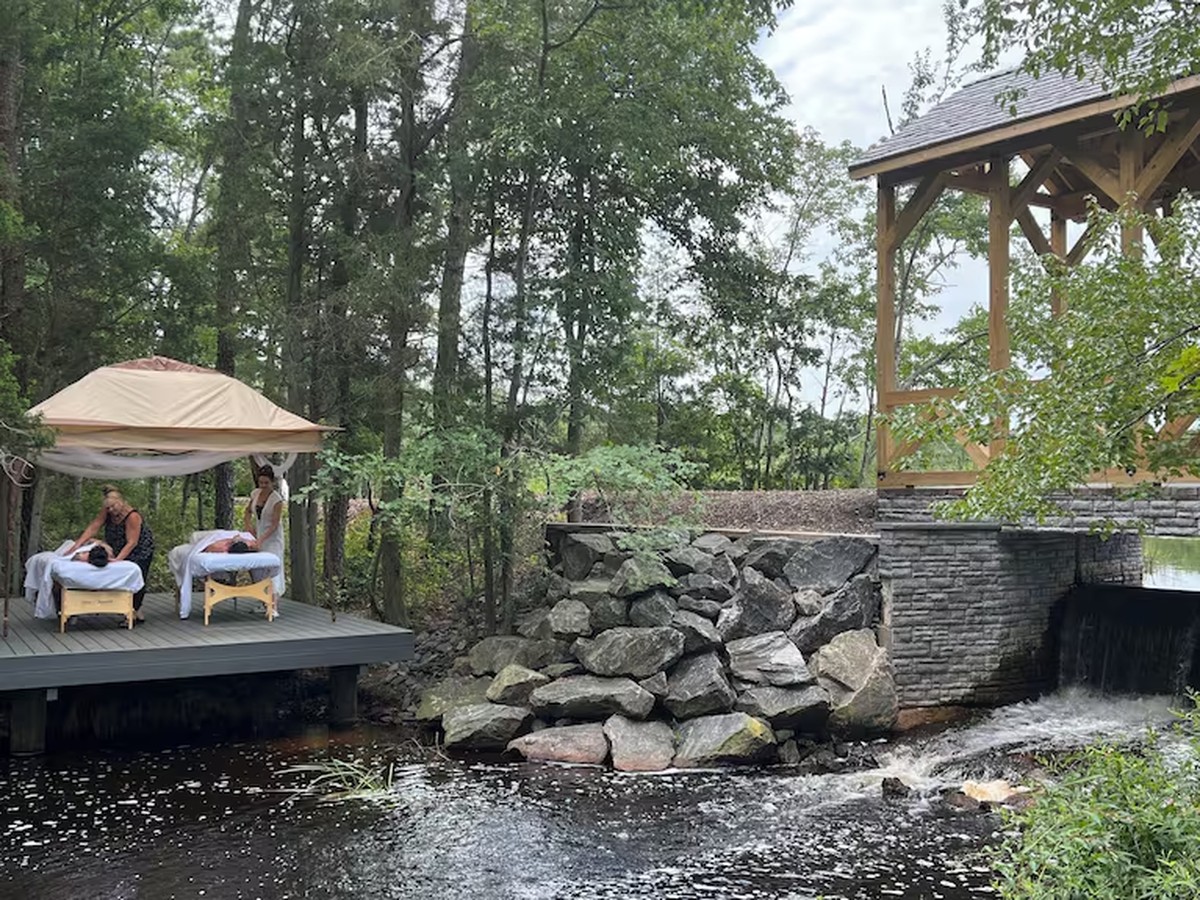 Couples massage on a lakeside deck beside the covered bridge at Swan Lake Resort